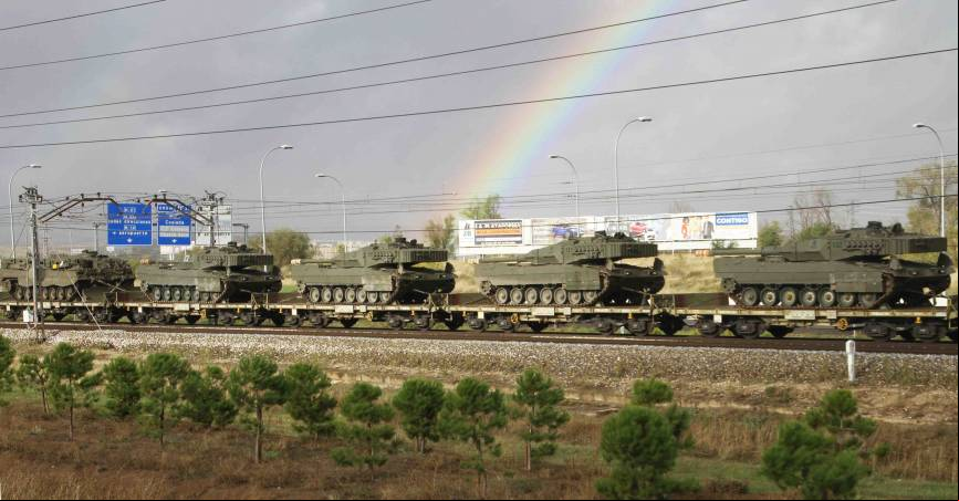 Con el arco iris de fondo avanza el tren cargado con carros Leopardo 2E (fotograf